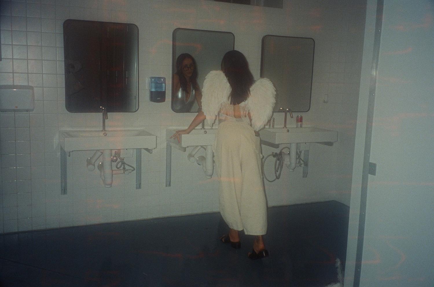 A performer in angel wings at the bathroom mirror