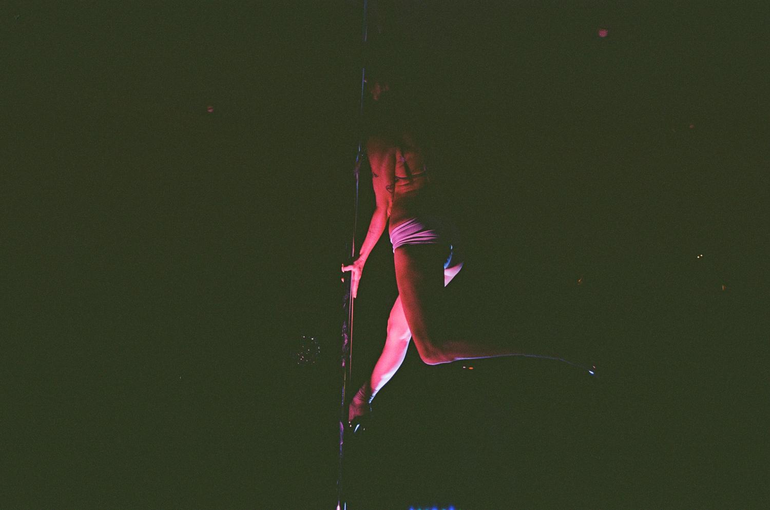 A dancer mid-spin on the pole in near darkness